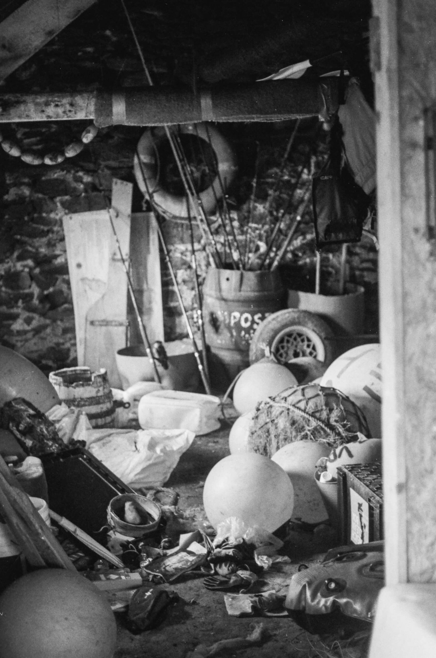 A cluttered storage room with fishing nets, floats, ropes, buoys, and miscellaneous equipment scattered on the floor captures the essence of life on Enlli.